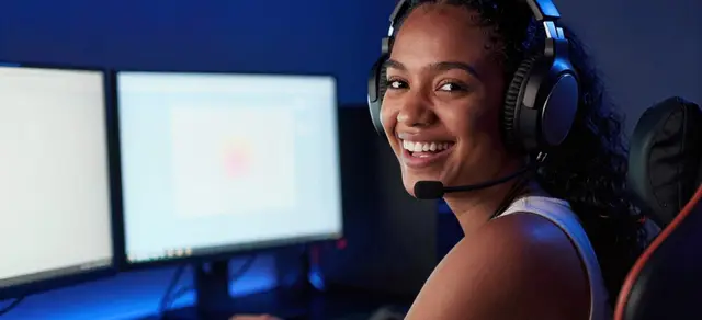 A streamer at a desk lit by screens